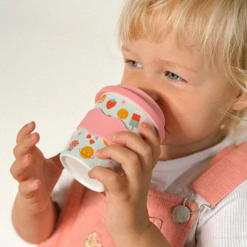Child holding a colorful cup with a pink handle against a plain background