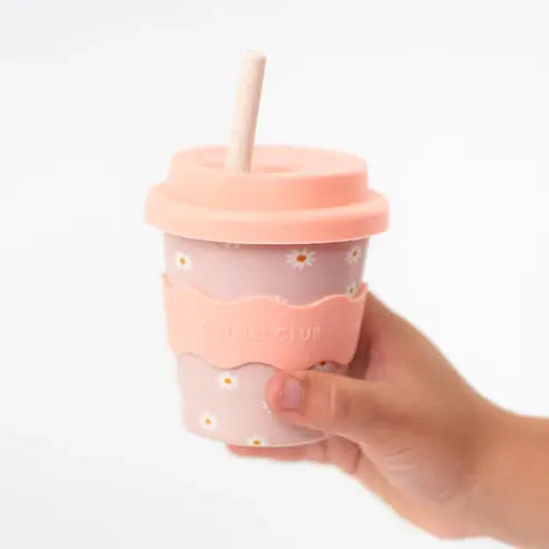 Hand holding a pink cup with a straw on a white background