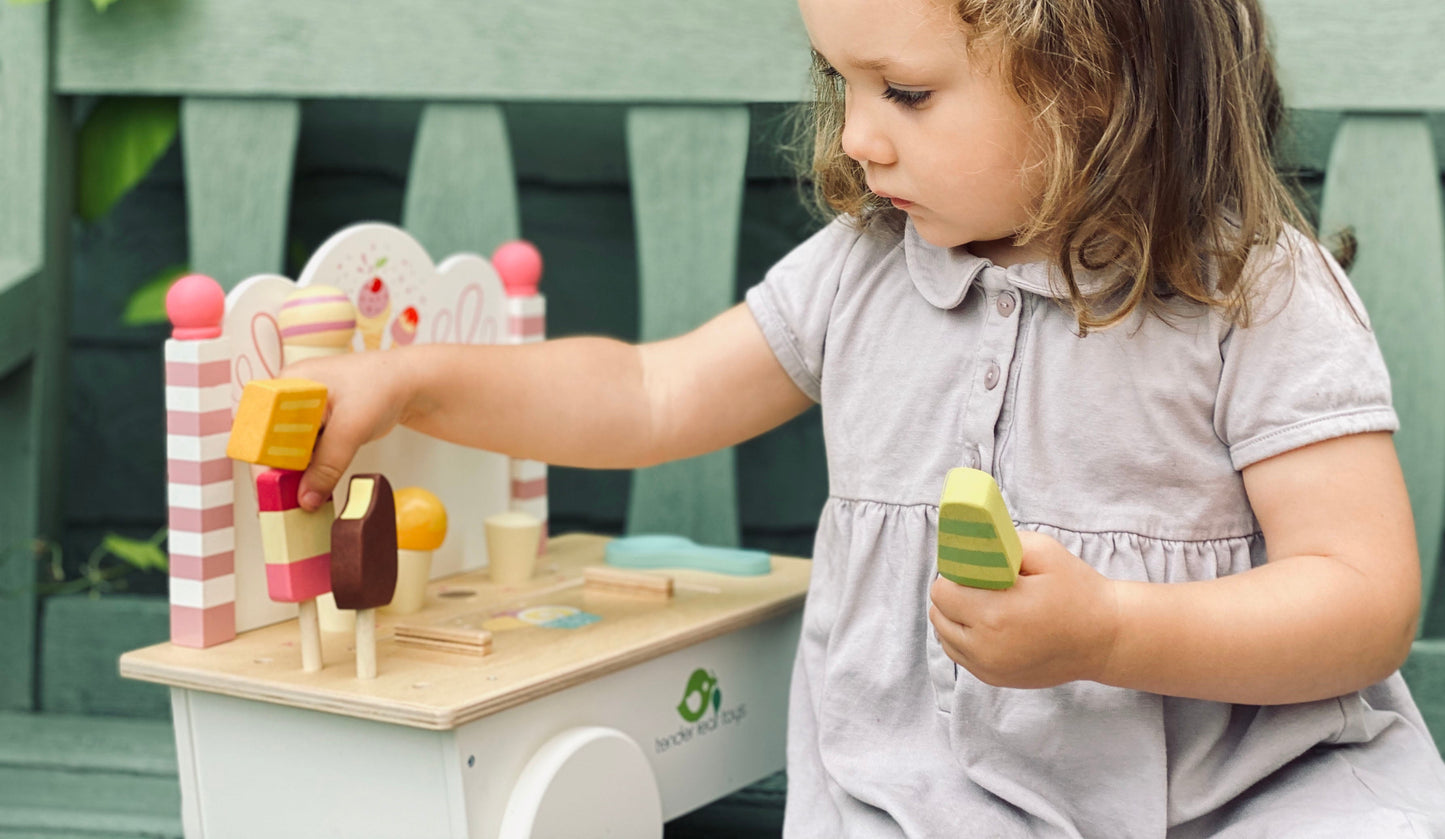 Child playing with wooden toys at a small table outdoors